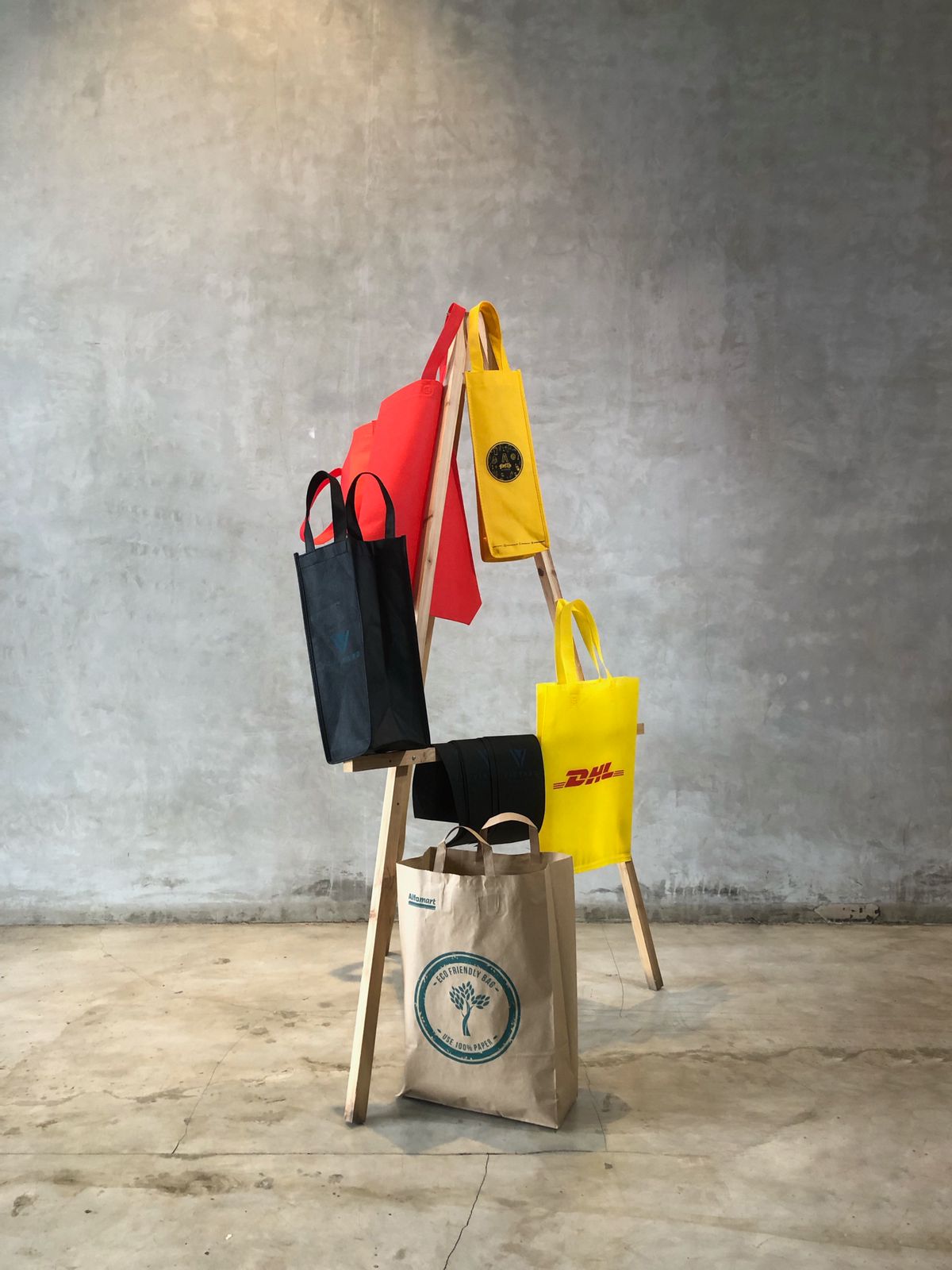 Pilihan tas dan goodie bag Rumah Pola ditata pada rak kayu